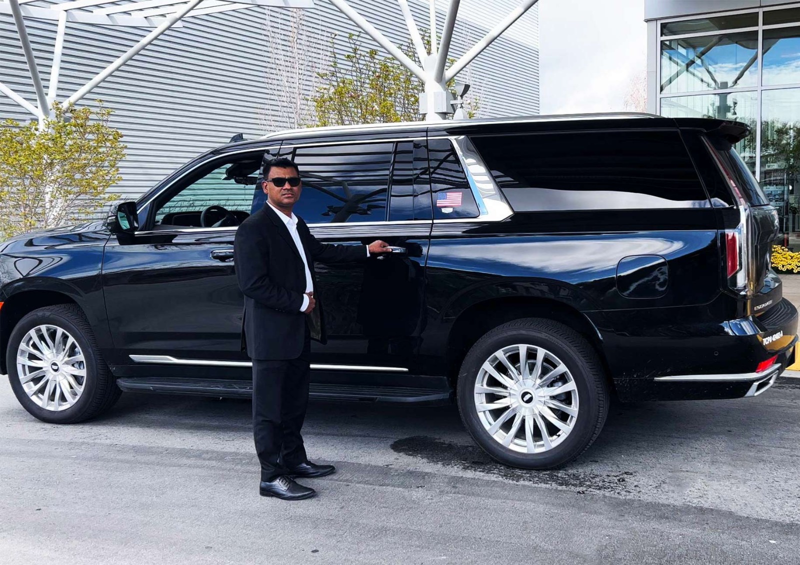 Chauffeur in a black suit standing beside a luxury black SUV at San Francisco International Airport, ready to assist passengers with premium car service