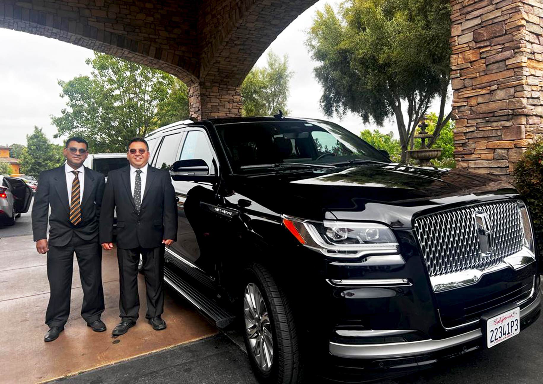 Two professional chauffeurs standing beside luxury SUVs, showcasing premium car service for Dublin to SFO airport transfers.