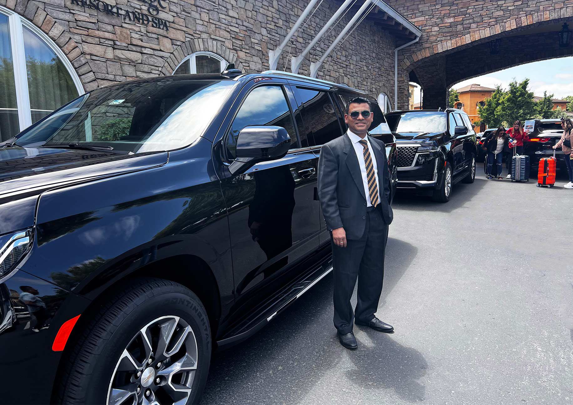 Professional chauffeur in a suit standing beside a luxury SUV, offering premium limo and car service from Swanton to SFO and SJC.