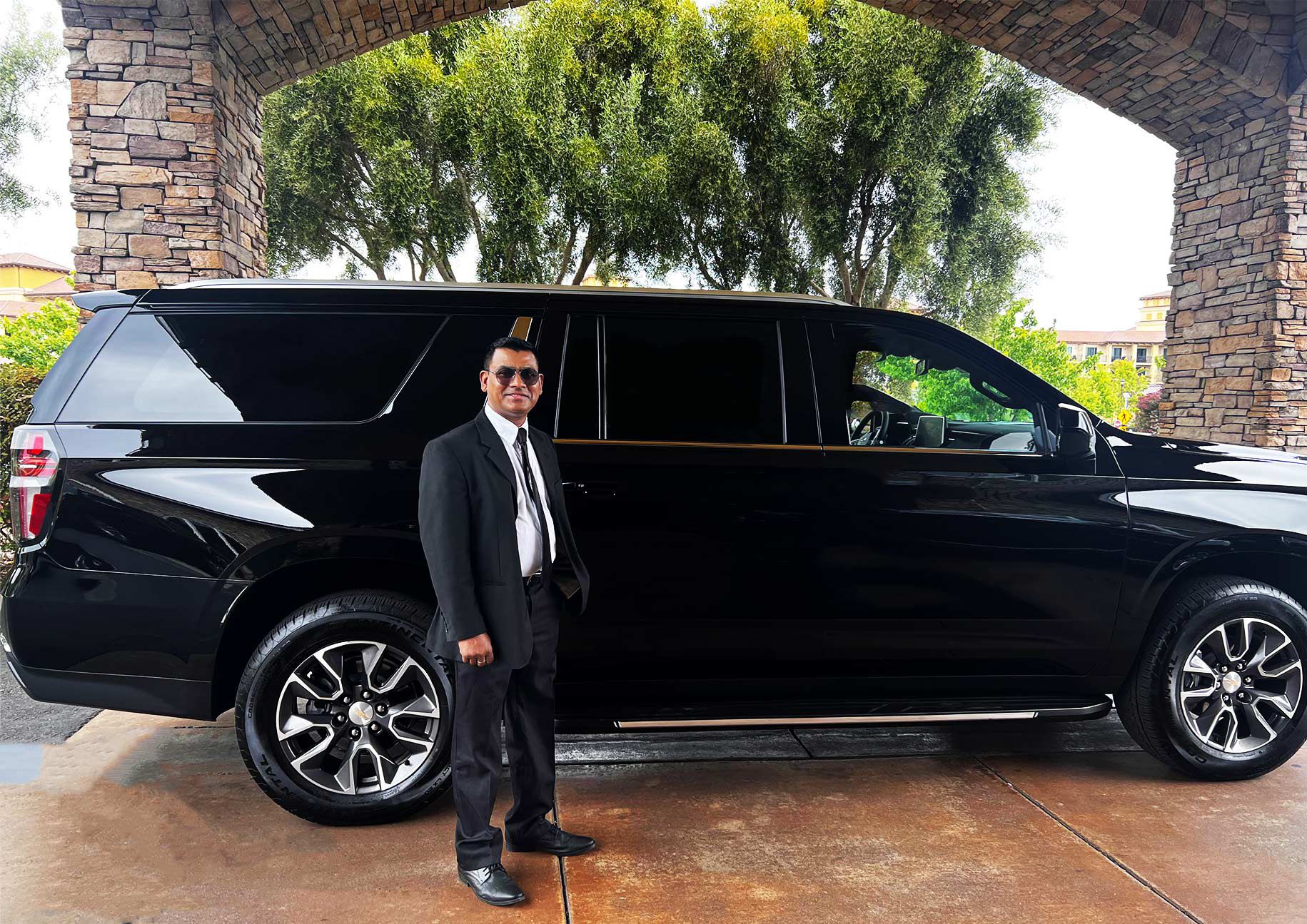 Professional chauffeur in a black suit standing beside a luxury black SUV, providing private chauffeur service at San Francisco International Airport (SFO)