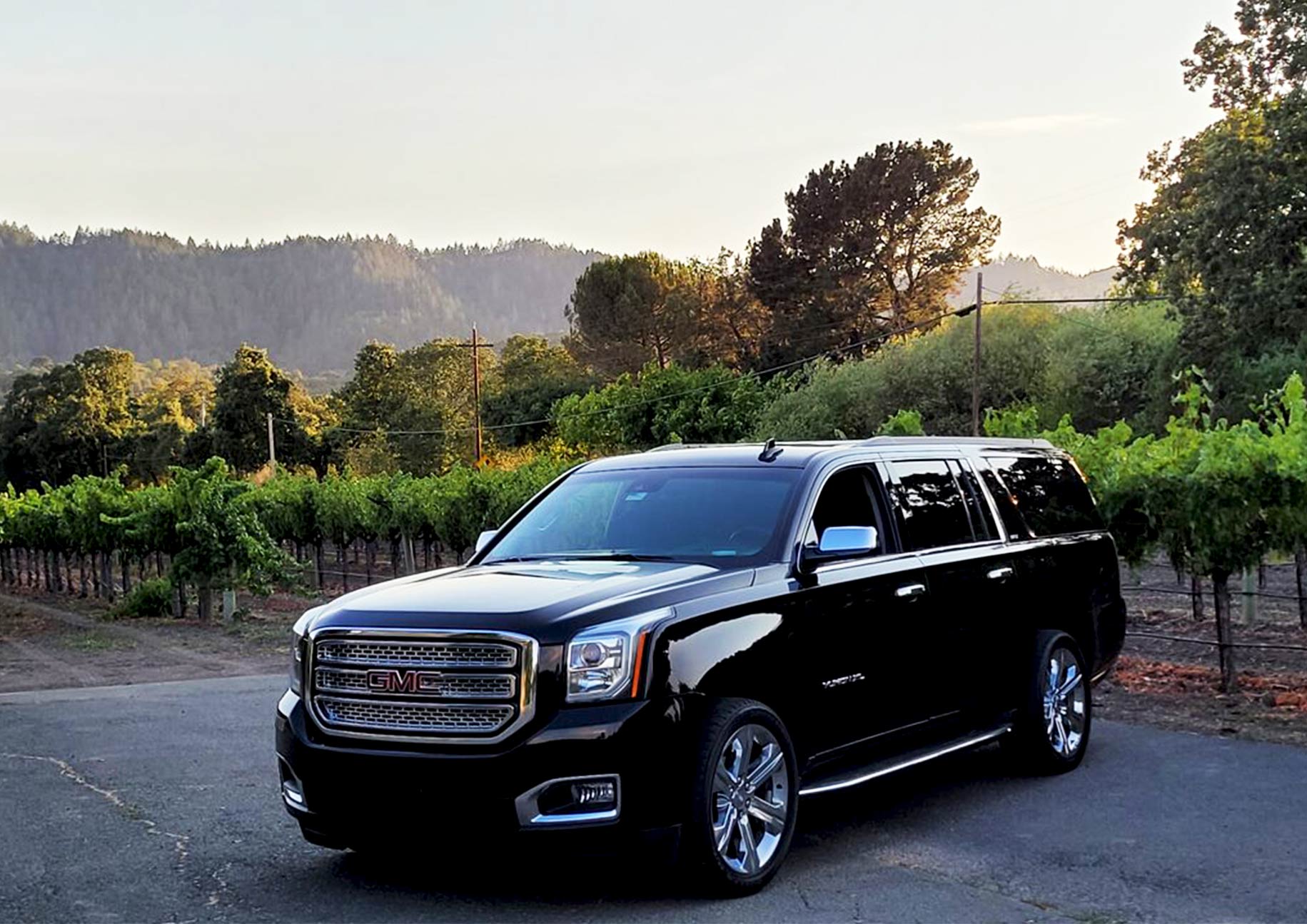 Black GMC Yukon XL parked at a scenic vineyard during sunset, ready for a luxurious Carmel wine tour