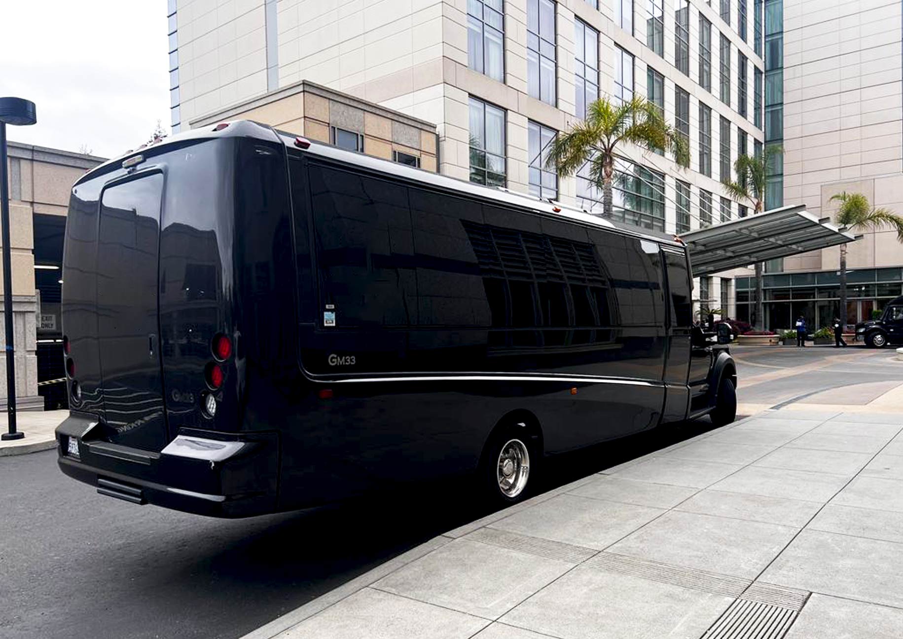 Luxury black GM33 mini coach parked at hotel entrance for group transportation